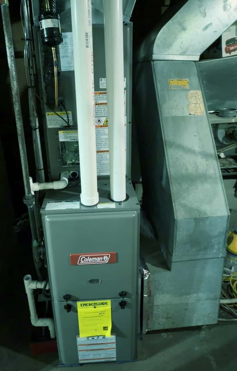 New high-efficiency gas furnace with white plastic vent pipes in the same basement