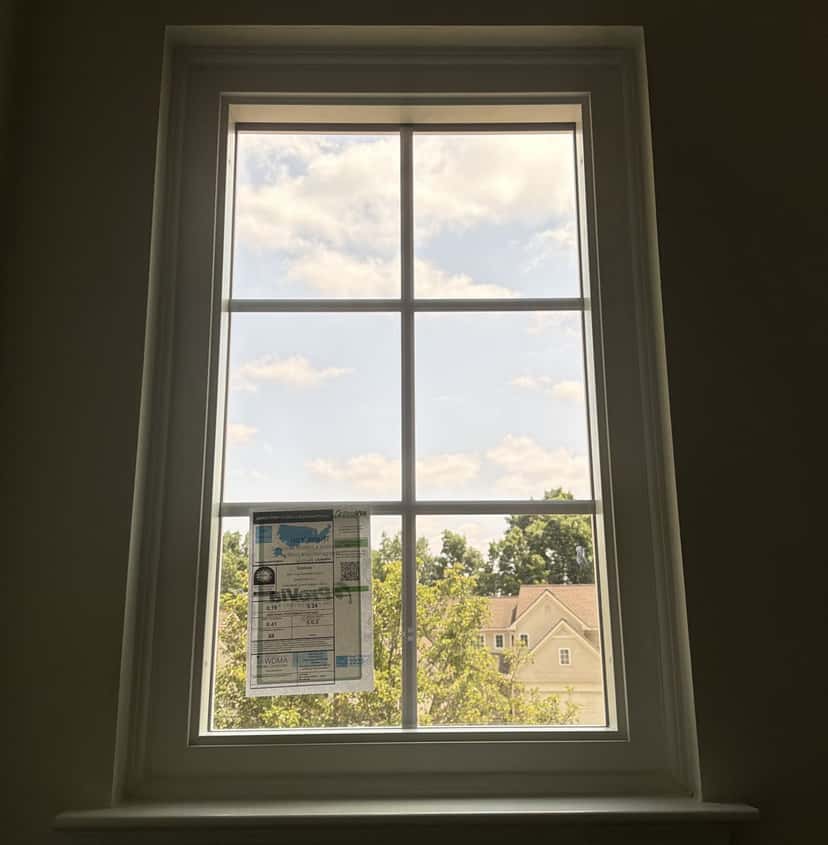 Replacement double-hung window with clear glass and its energy rating label still on the pane