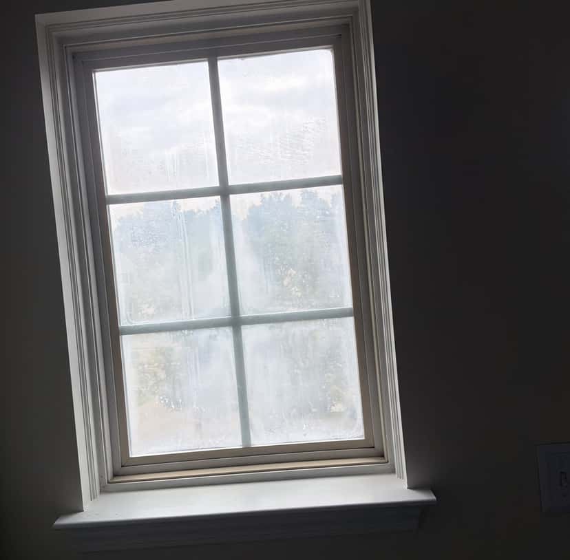 Old double-pane window with fog trapped between the panes from a failed seal