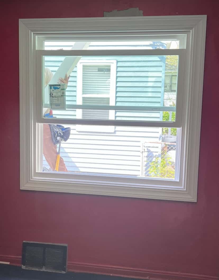 New double-hung replacement window with its energy rating label, installed in the same bedroom wall